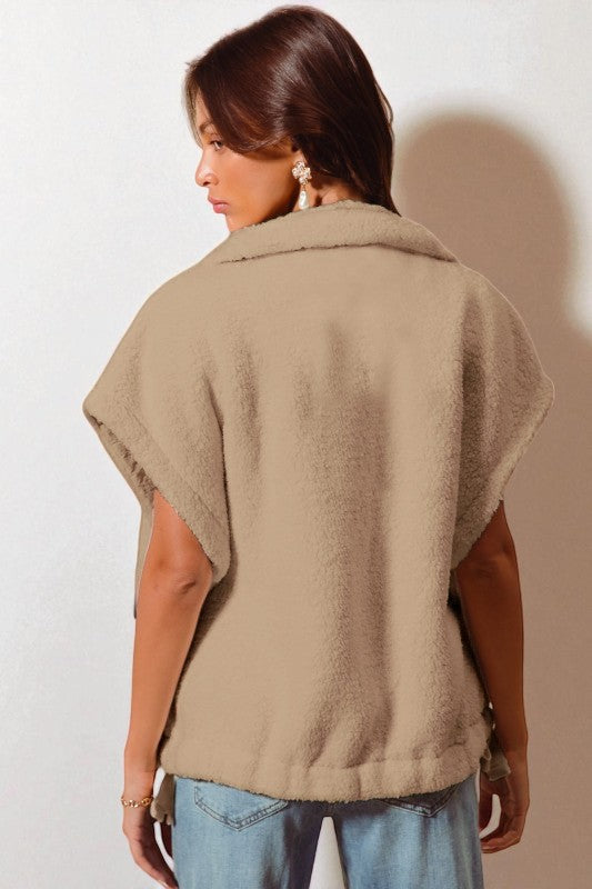 Woman wearing a beige poncho against a plain background