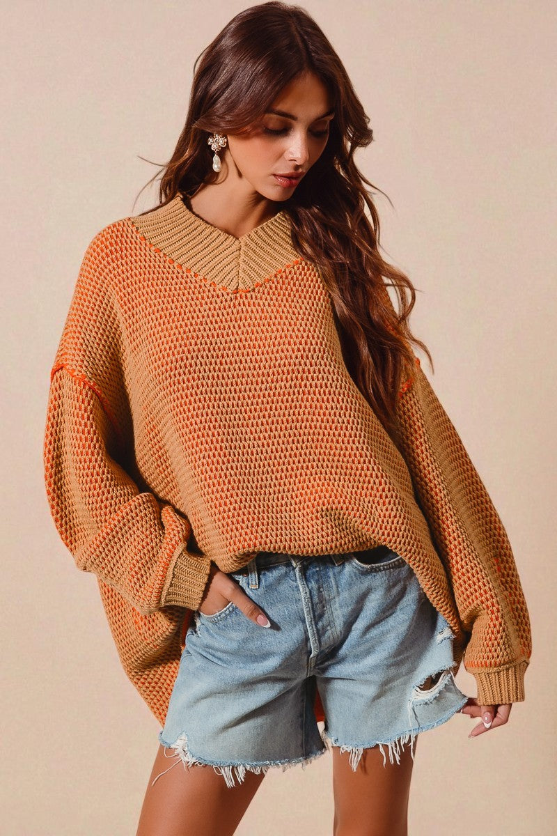 Woman wearing a mustard yellow sweater and denim shorts against a beige background