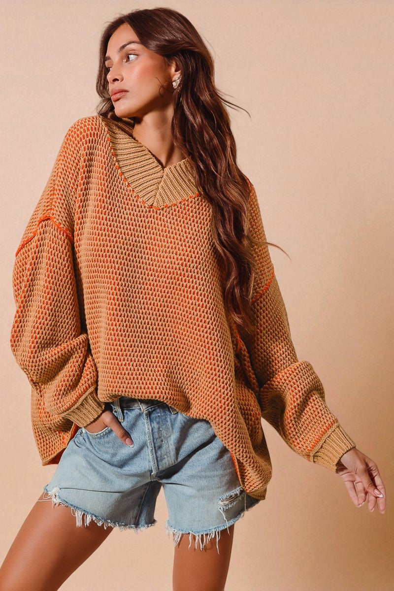 Woman wearing a brown oversized sweater and denim shorts against a beige background