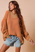 Woman wearing a brown oversized sweater and denim shorts against a beige background