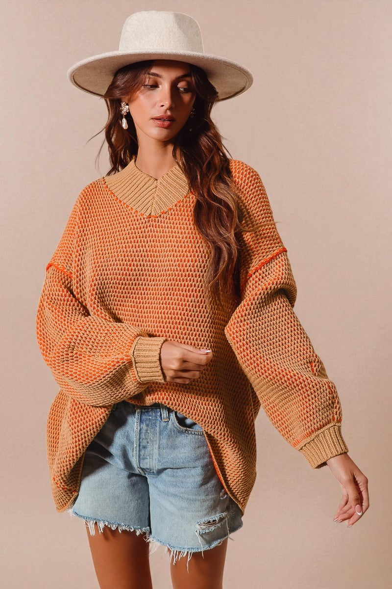 Woman wearing an orange sweater, denim shorts, and a white hat on a beige background