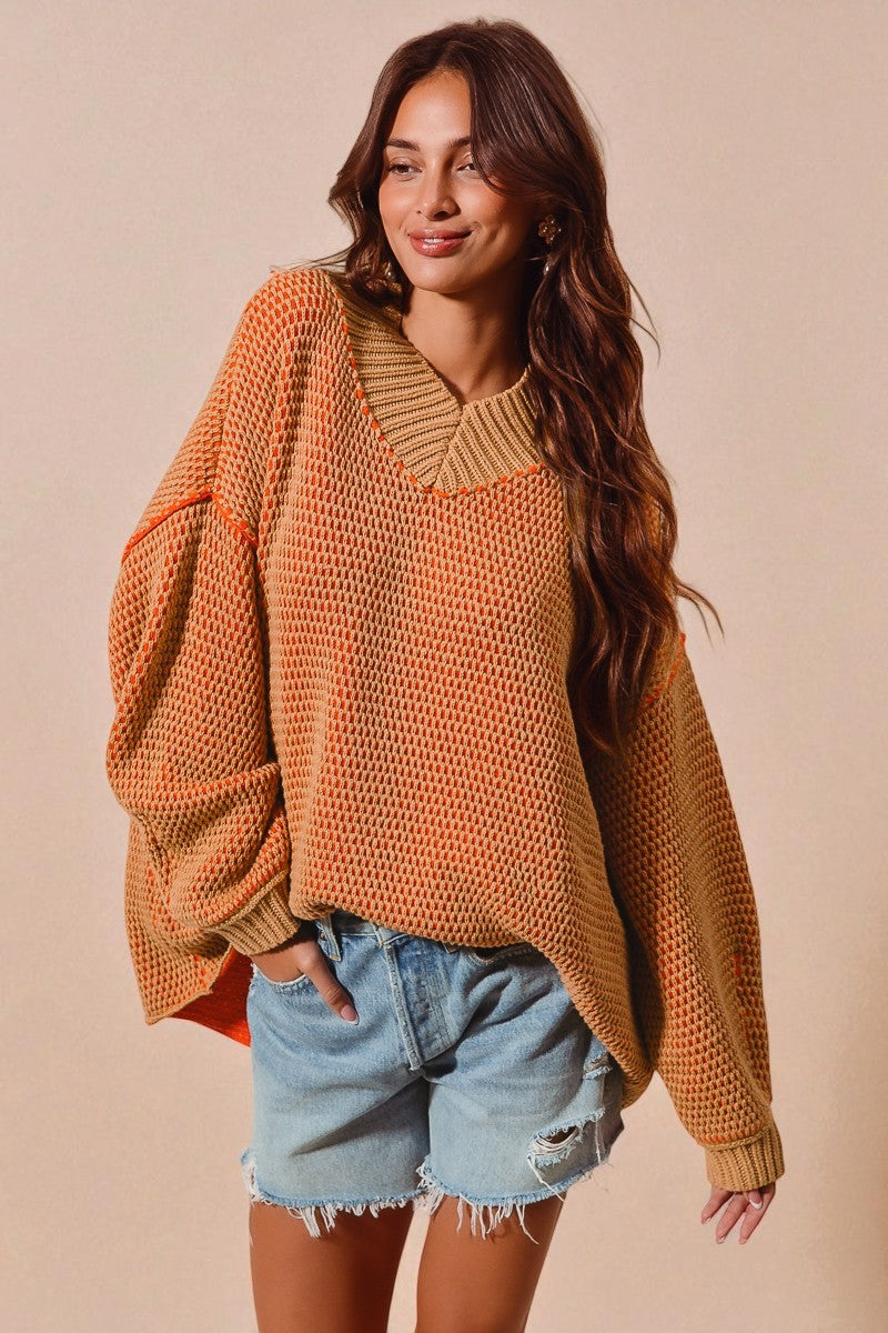 Woman wearing a mustard yellow knit sweater and denim shorts against a beige background