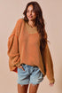 Woman wearing a mustard yellow knit sweater and denim shorts against a beige background