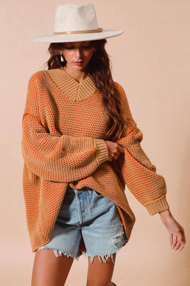 Woman wearing a brown sweater with a collar and denim shorts against a beige background