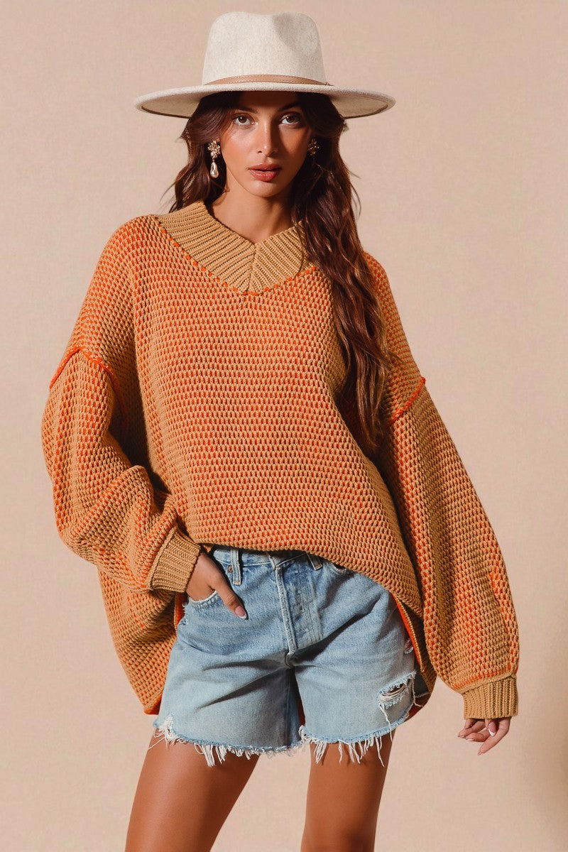 Woman wearing an orange sweater and denim shorts with a beige background