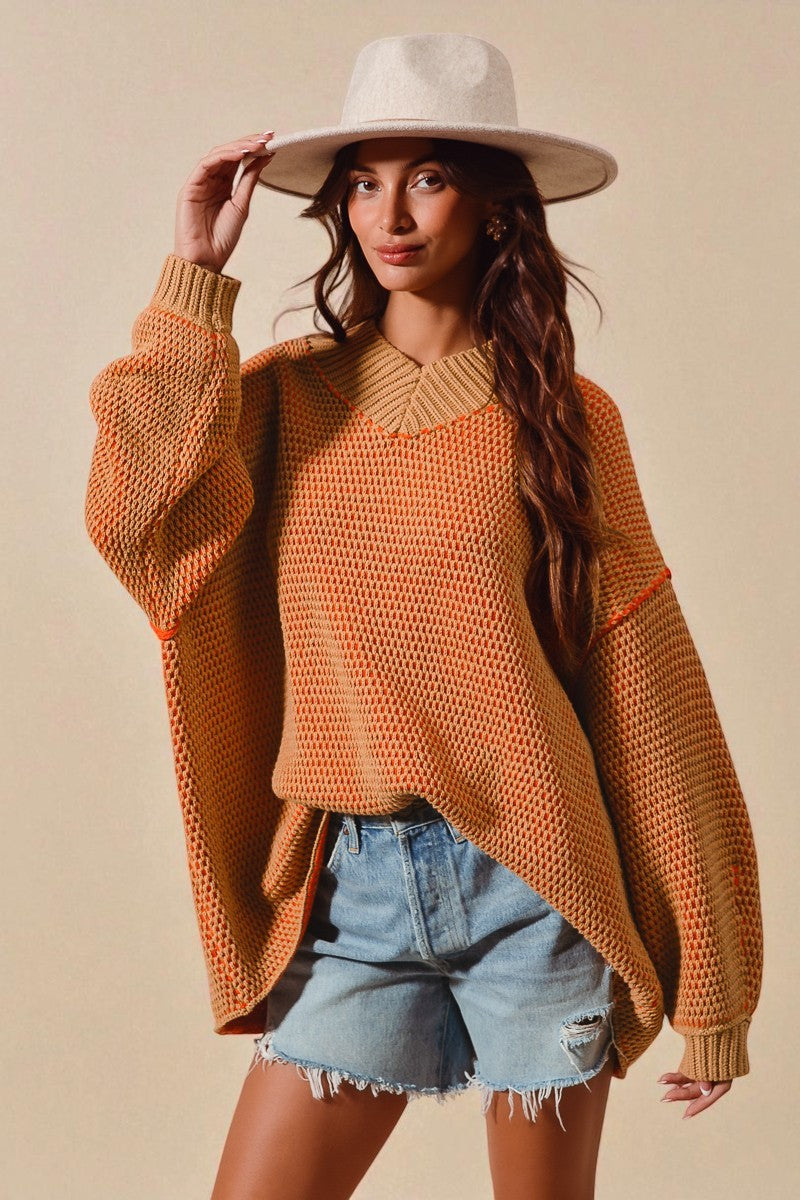 Woman wearing a mustard yellow sweater, denim shorts, and a white hat against a beige background