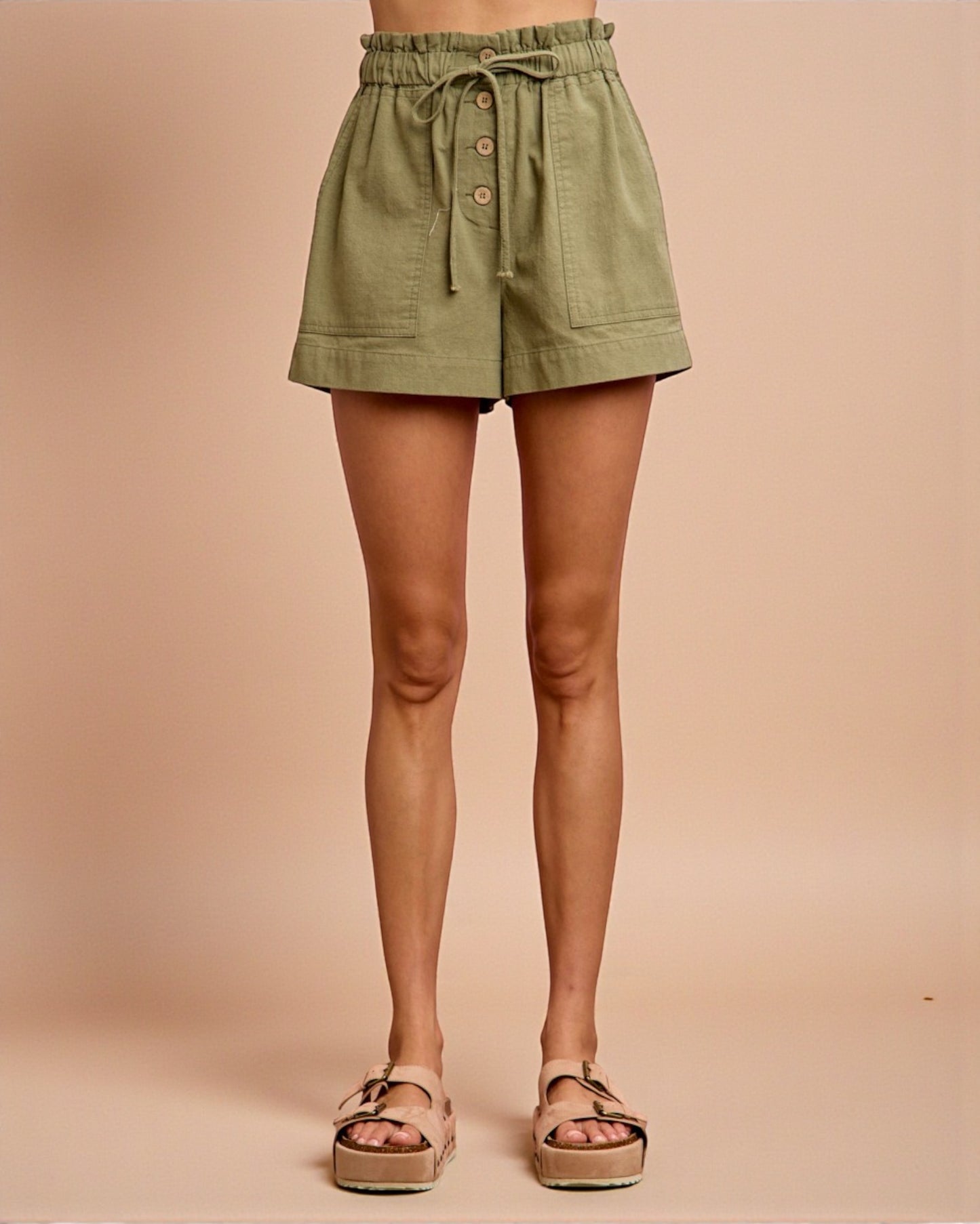 Green shorts worn by a person on a beige background