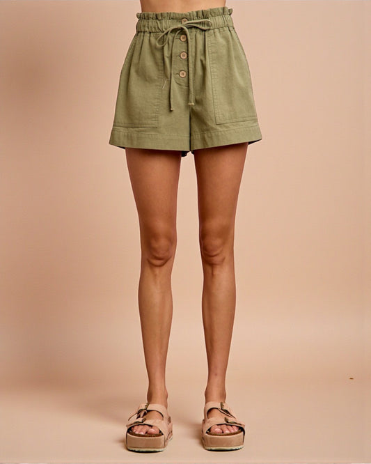 Green shorts worn by a person on a beige background