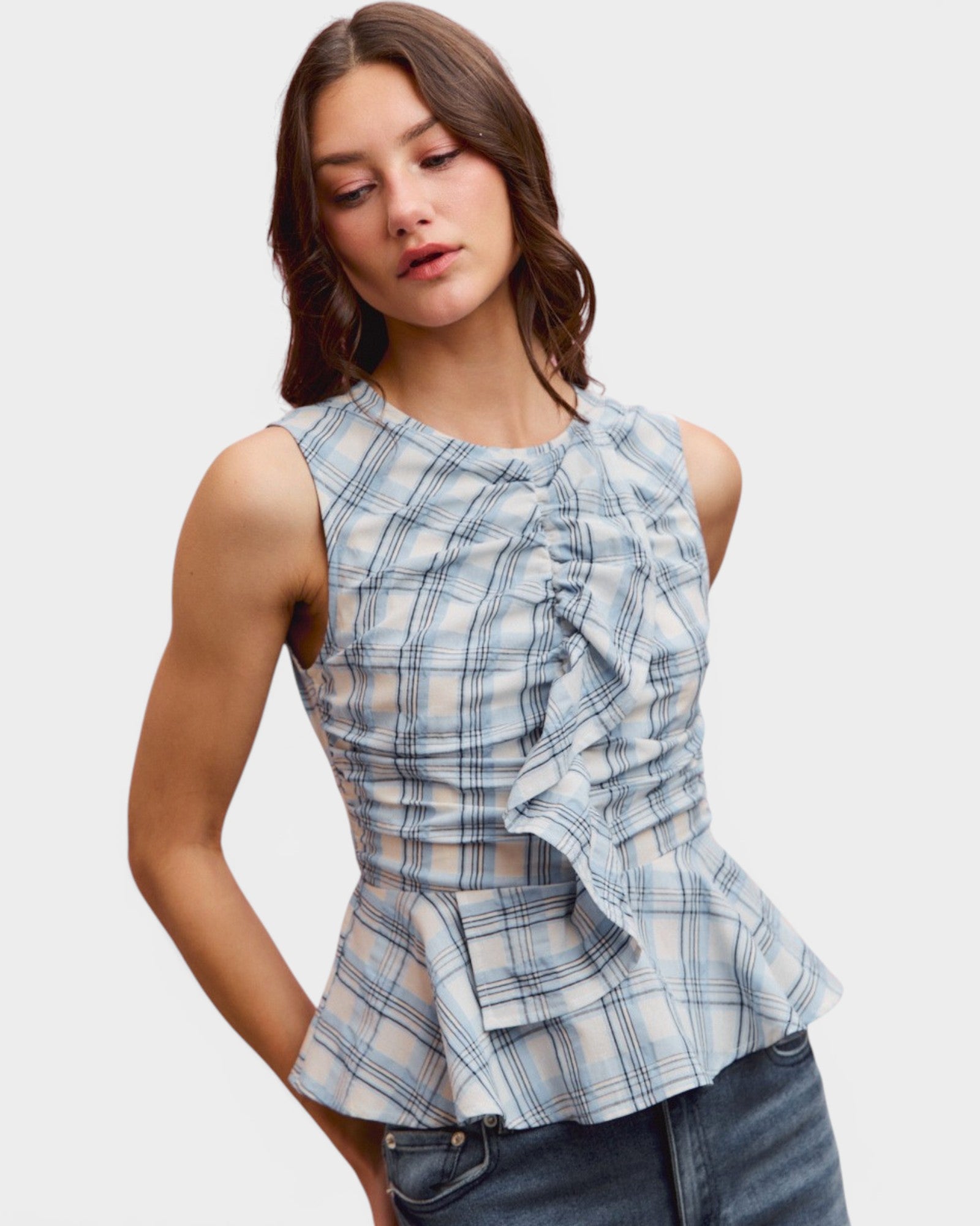 Woman wearing a blue plaid top with ruffle details on a white background