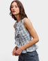 Woman wearing a plaid sleeveless top and jeans on a white background