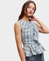 Woman wearing a blue plaid top with ruffle details on a white background