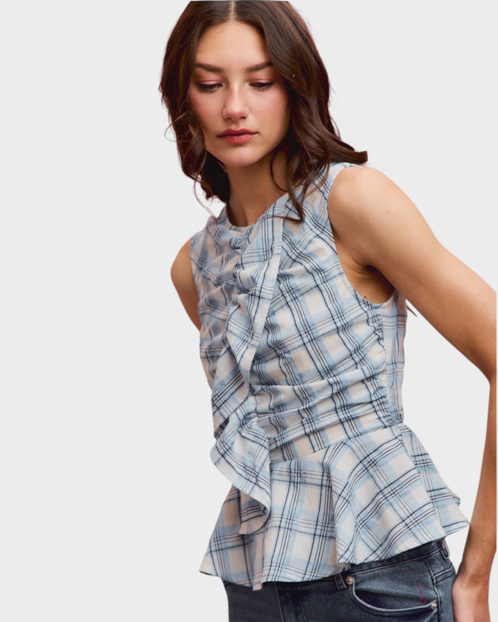 Woman wearing a blue plaid peplum top on a white background