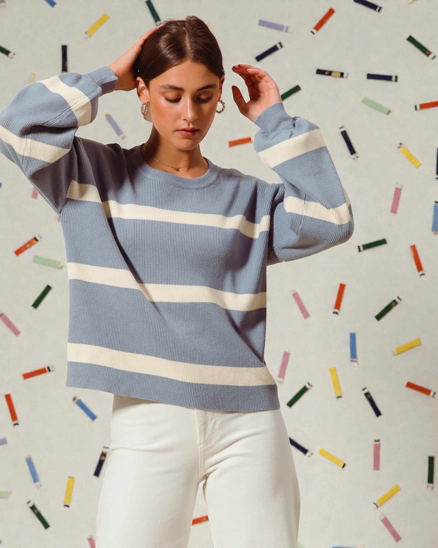 Woman wearing a blue and white striped sweater with a colorful confetti background