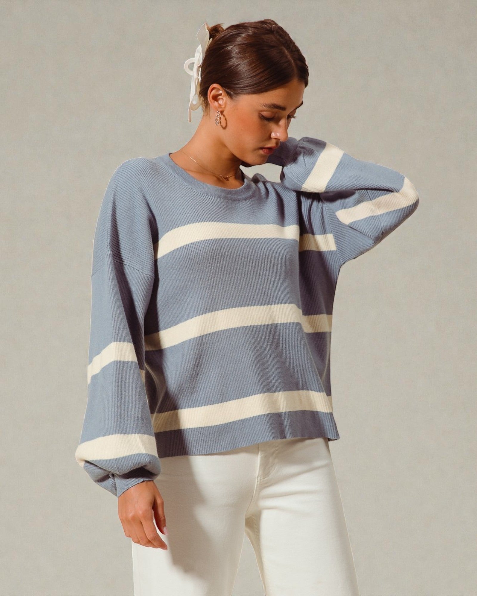 Woman wearing a blue sweater with white stripes against a plain background
