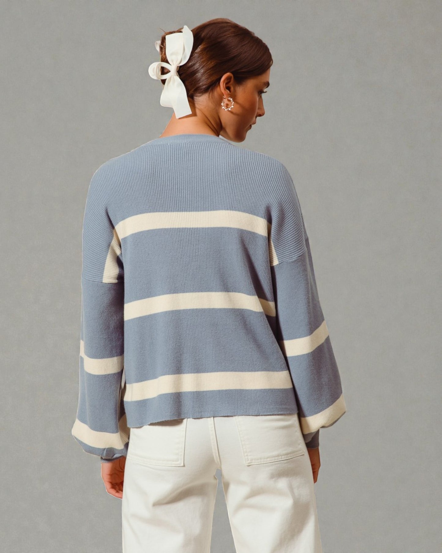 Person wearing a blue sweater with white stripes on a gray background