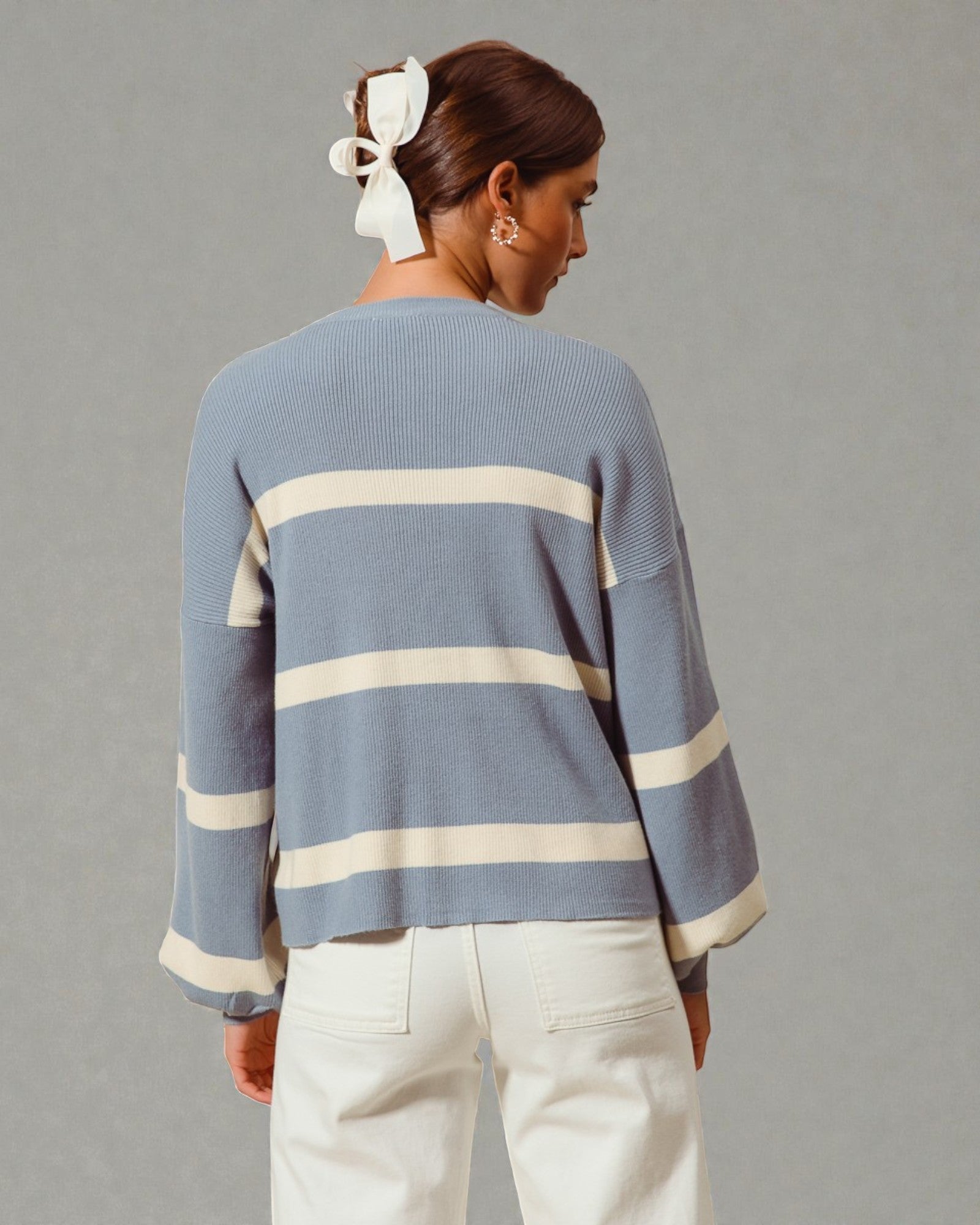 Person wearing a blue sweater with white stripes on a gray background