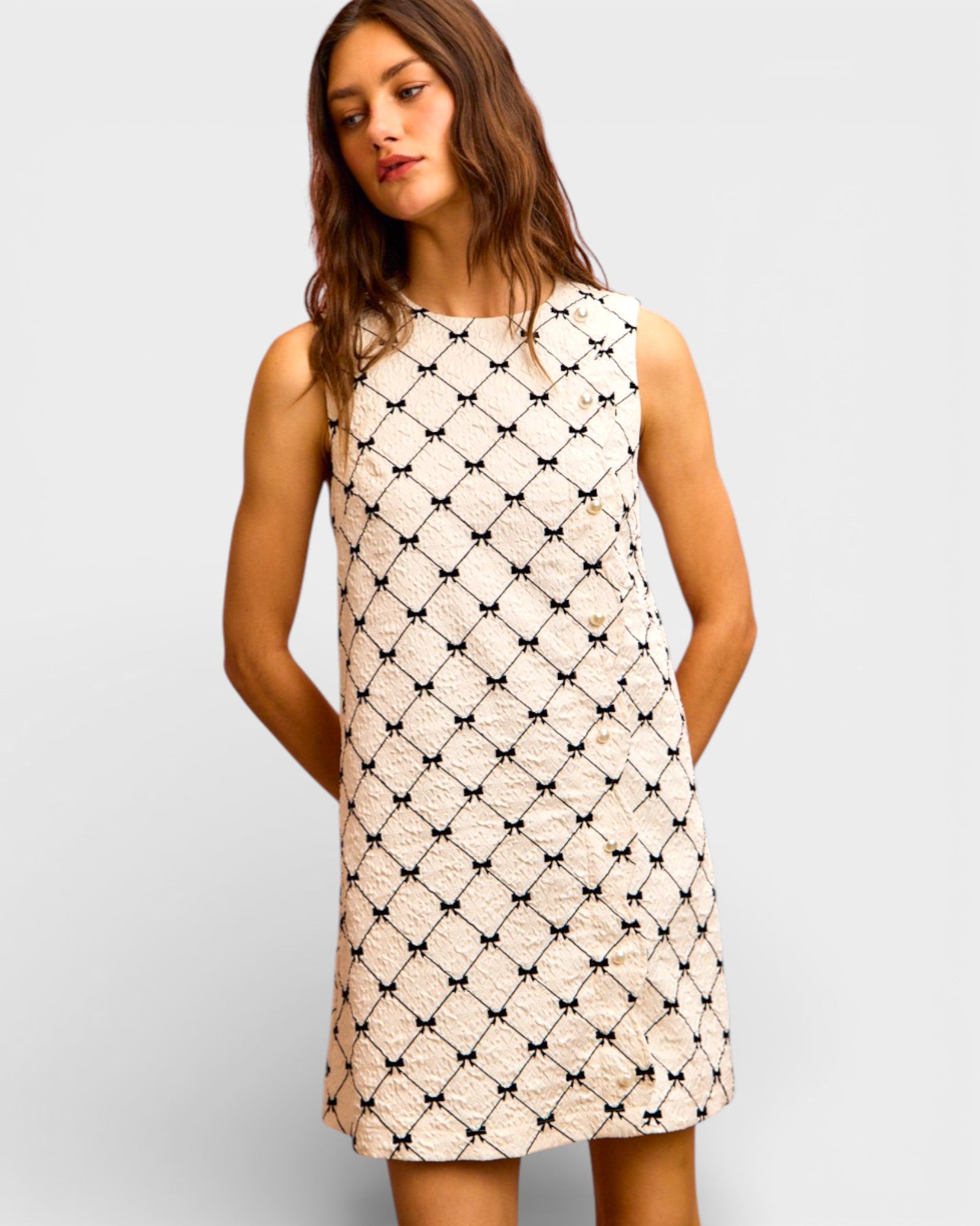 Woman wearing a sleeveless dress with a geometric pattern on a plain background