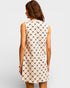 Woman wearing a sleeveless dress with a geometric pattern on a plain background