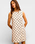 Woman wearing a sleeveless dress with a geometric pattern on a plain background
