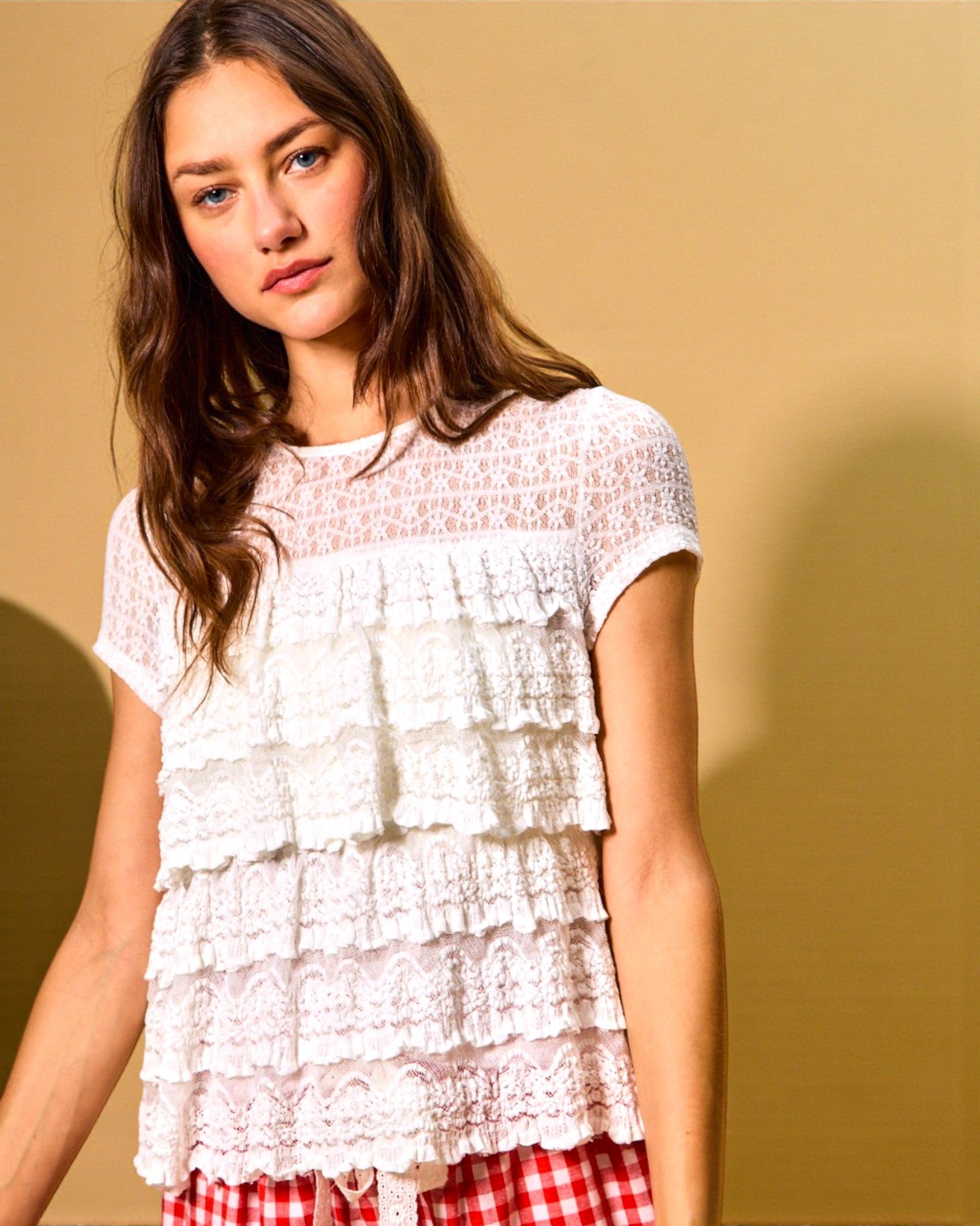 Woman wearing a white lace top with a plain background