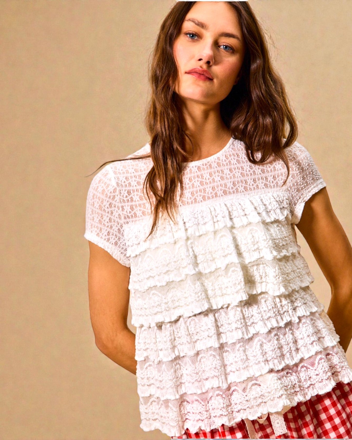 Woman wearing a white lace top with a beige background