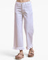 White cropped wide-leg jeans with a ruffled hem, shown on a model wearing brown platform sandals against a light gray background.