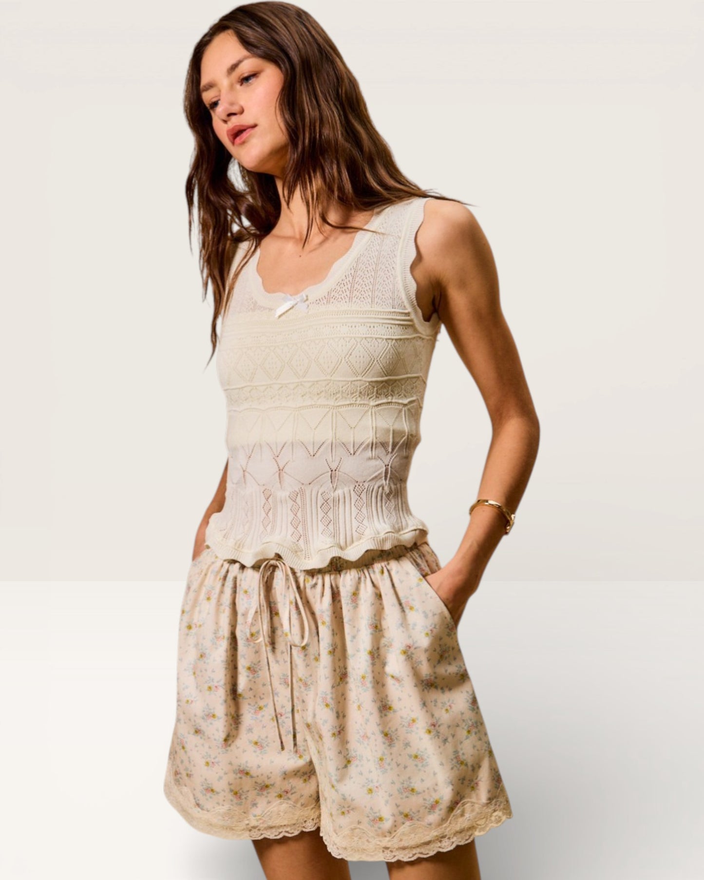 Woman wearing a sleeveless beige dress with floral pattern on a plain background