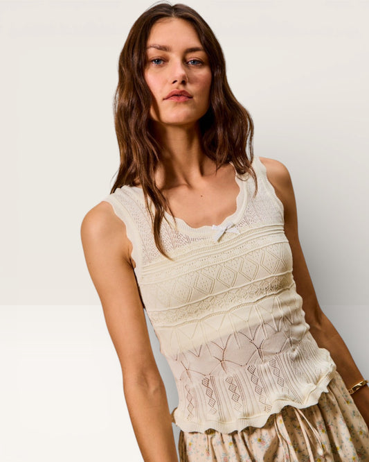 Woman wearing a white lace top against a plain background