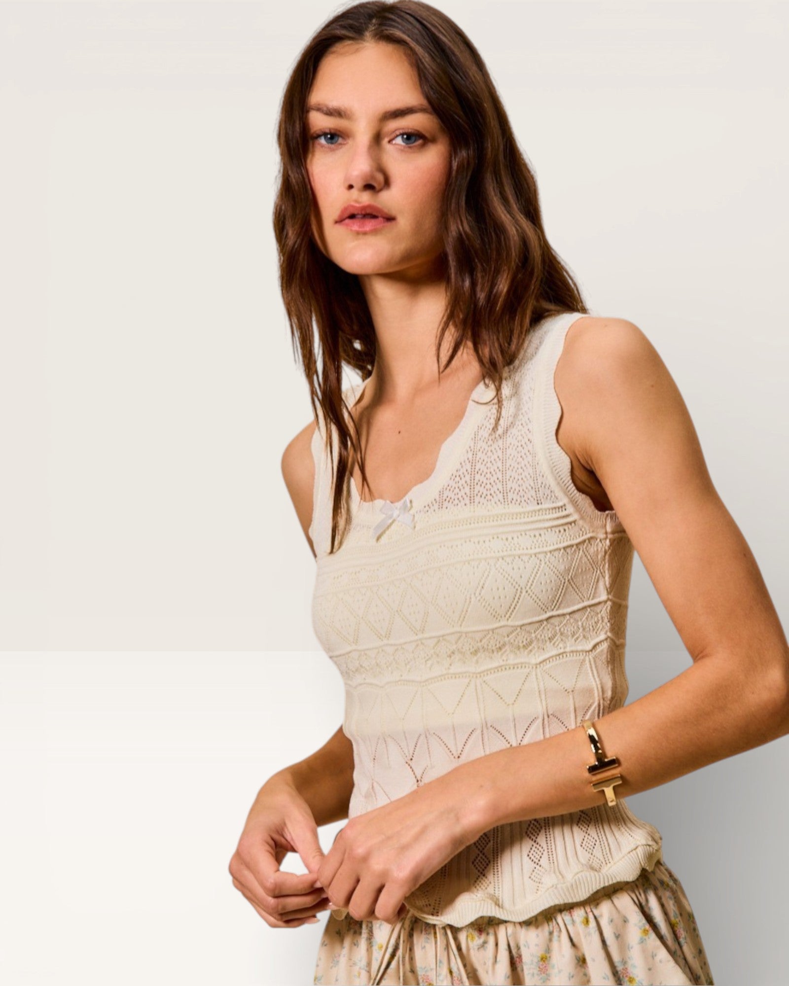 Woman wearing a beige sleeveless dress against a plain background