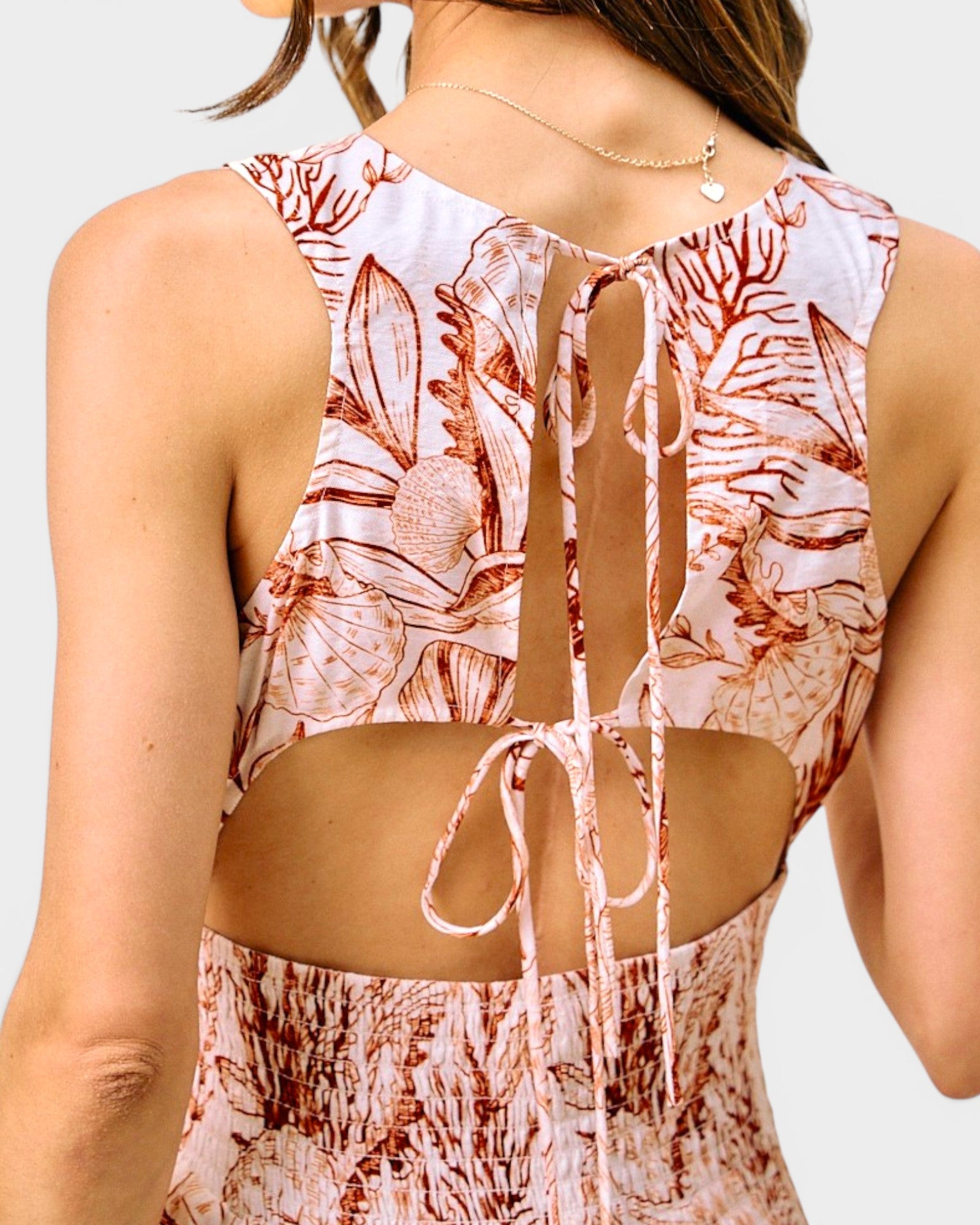 Woman wearing a floral tank top with cut-out design on a light gray background