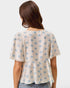 Woman wearing a polka dot blouse with short sleeves on a plain background