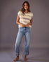 Woman wearing a striped sleeveless top and blue jeans against a gray background