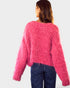 Person wearing a pink fuzzy sweater and blue jeans on a white background
