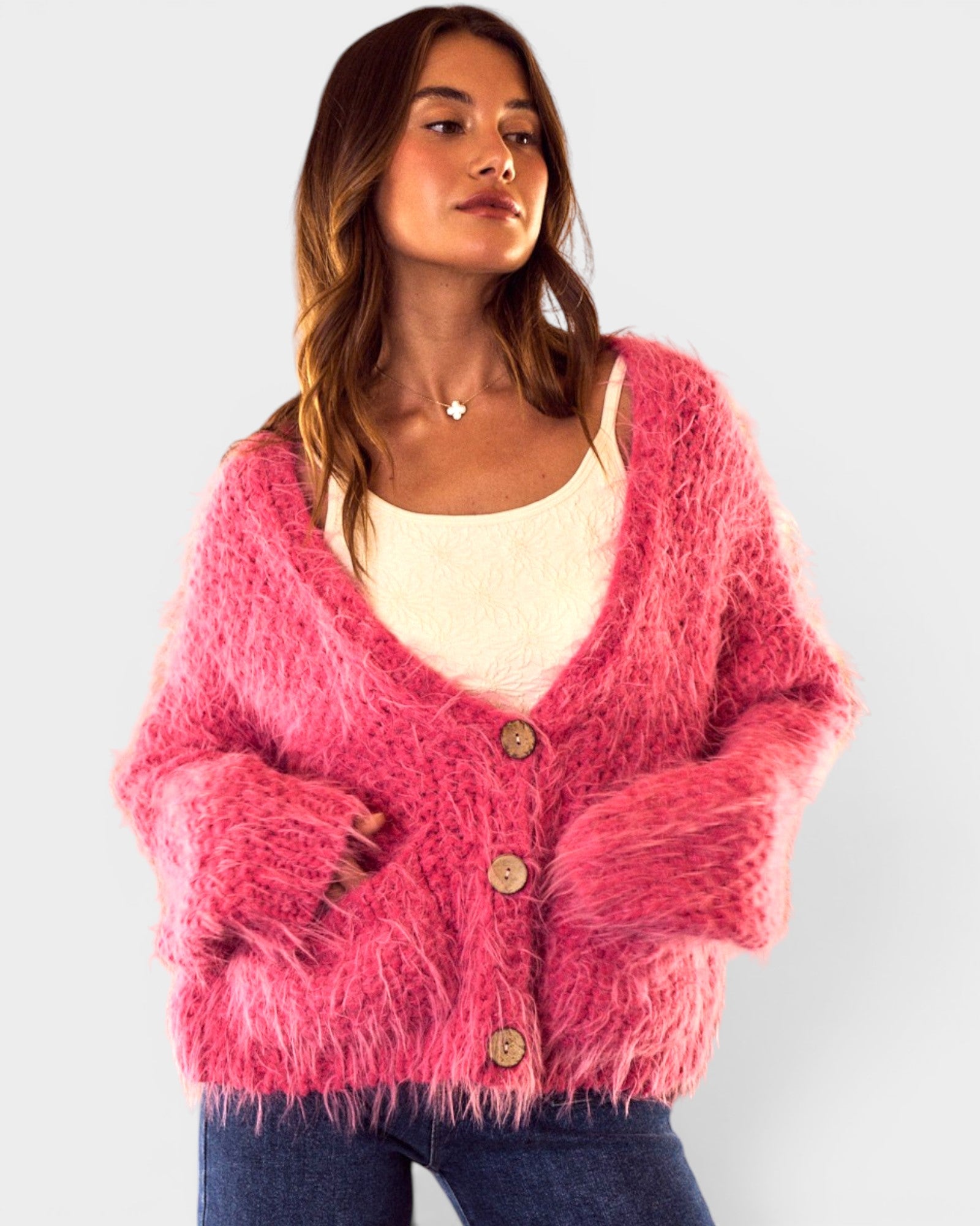 Woman wearing a pink fuzzy cardigan on a light gray background