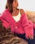 Woman wearing a pink fuzzy cardigan sitting on a couch.