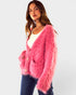 Woman wearing a pink fuzzy cardigan on a white background