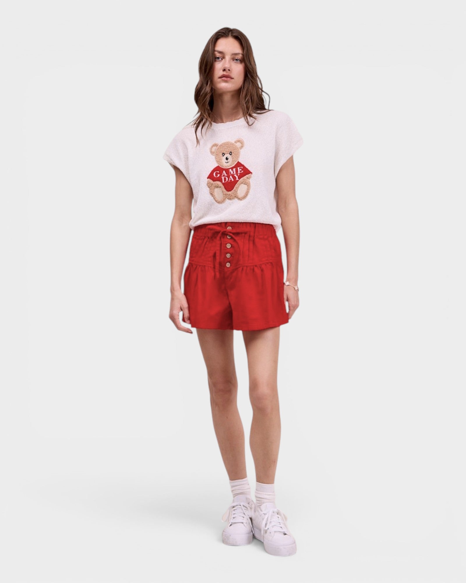 Woman wearing a white t-shirt with a bear graphic and red shorts on a white background