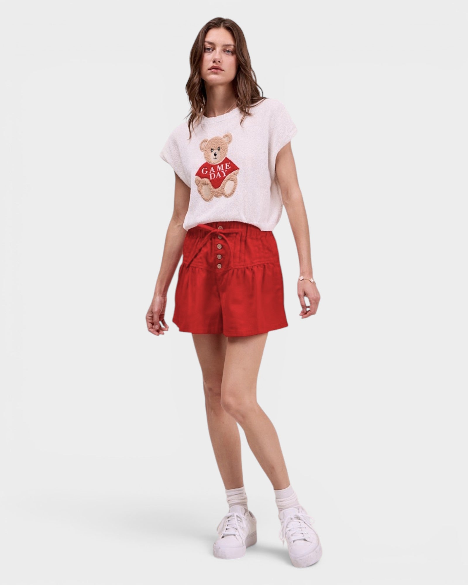 Woman wearing a white t-shirt with a teddy bear graphic and red shorts on a white background