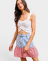 Woman wearing a white top and a denim skirt with star pattern and red and white striped hem on a white background