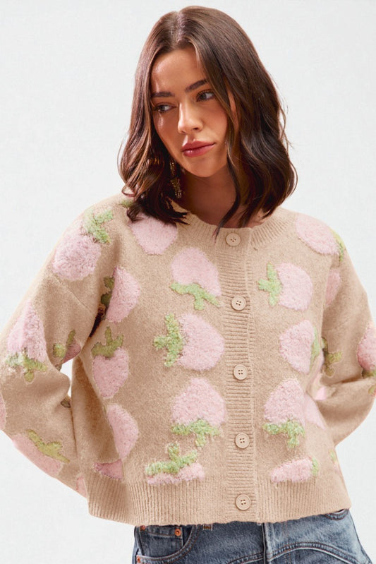 Woman wearing a beige cardigan with pink floral patterns on a white background