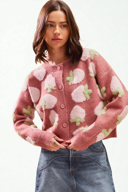 Woman wearing a pink cardigan with floral patterns on a white background