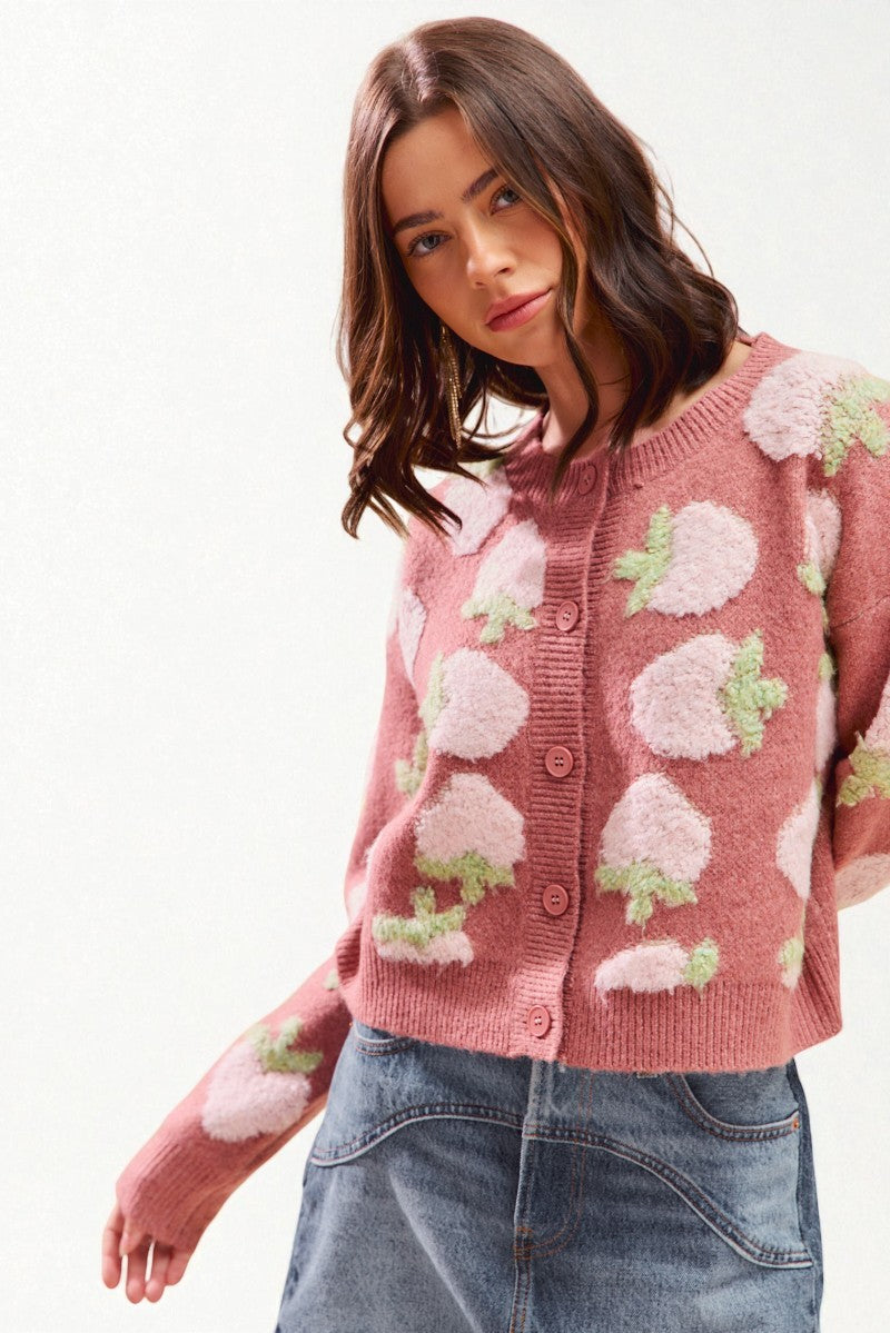 Woman wearing a pink cardigan with floral patterns on a white background