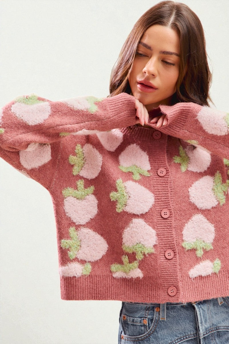 Woman wearing a pink cardigan with white floral patterns on a white background