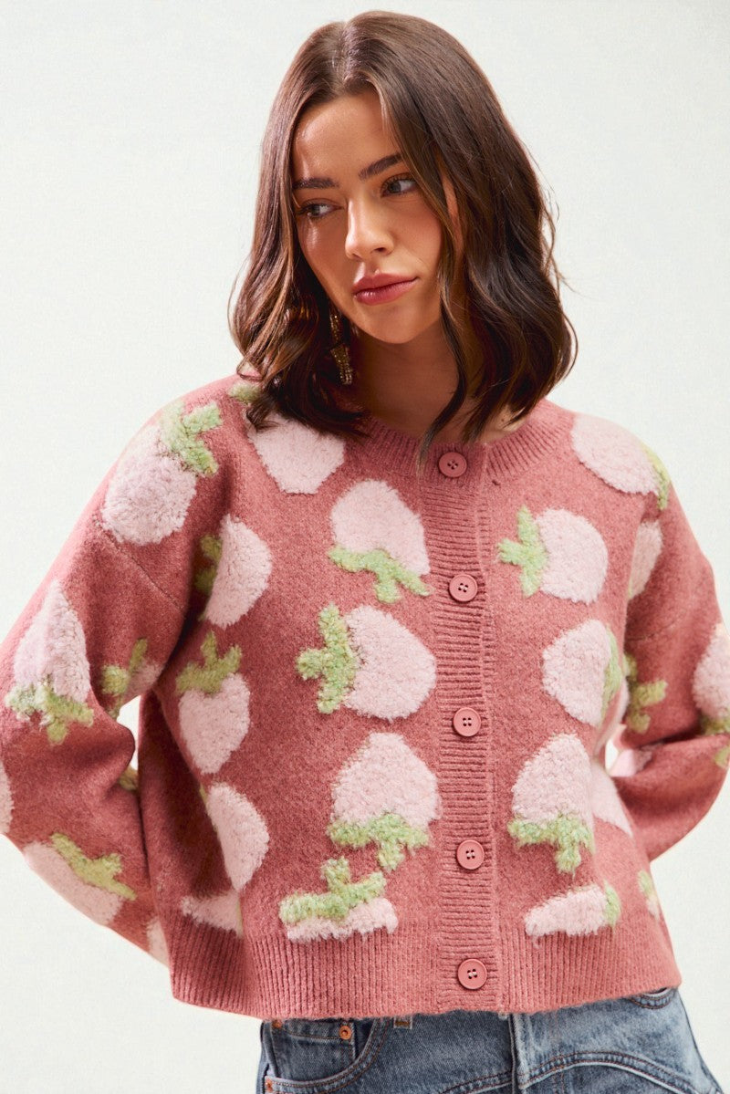Woman wearing a pink cardigan with floral patterns on a white background