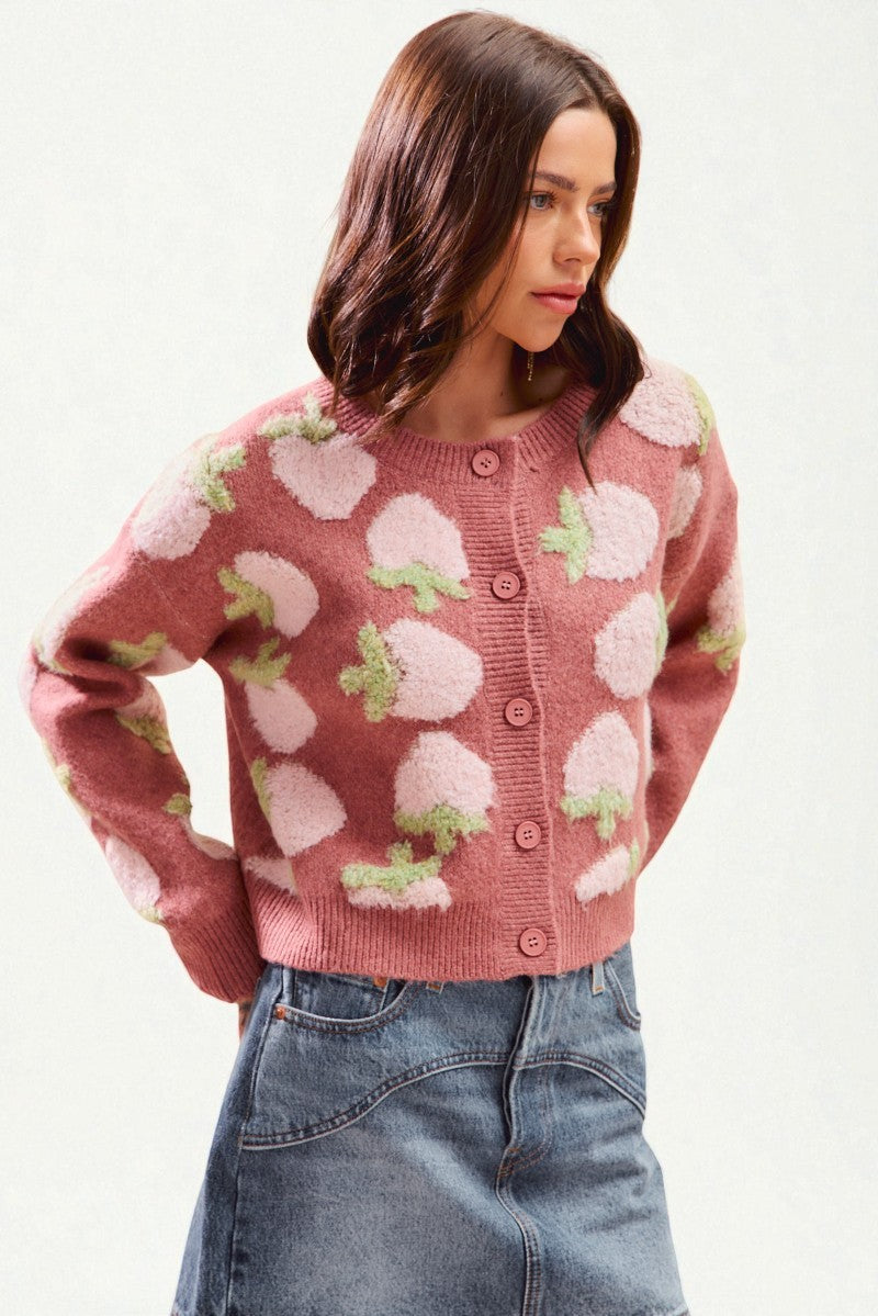 Woman wearing a pink sweater with floral patterns on a white background