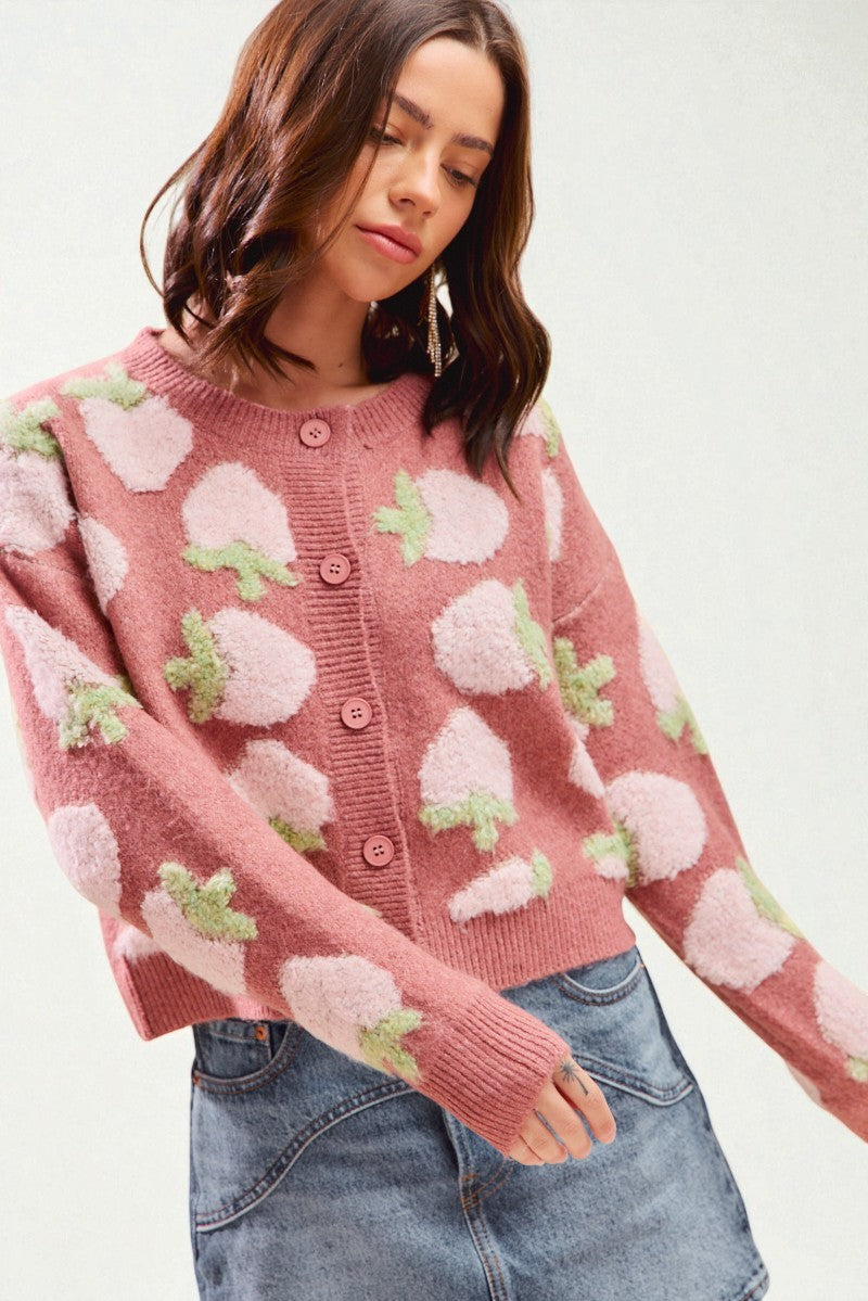 Woman wearing a pink sweater with floral patterns on a white background