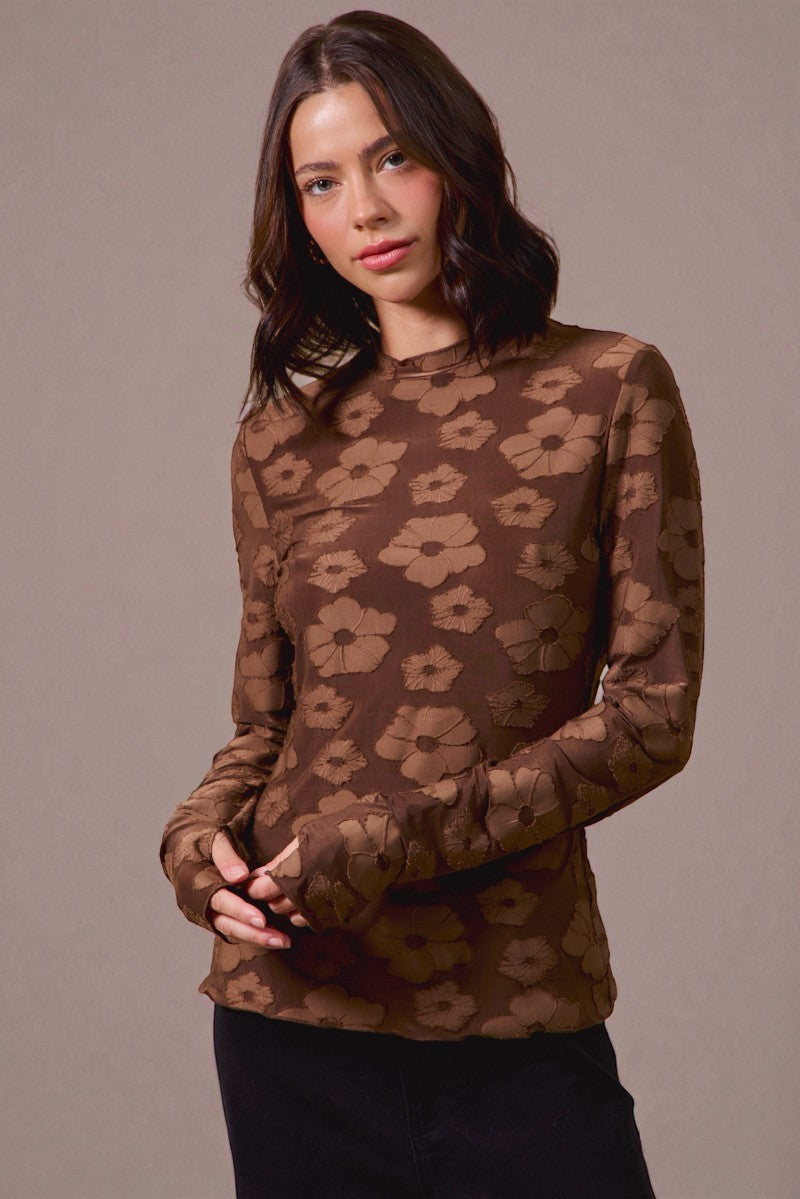 Woman wearing a brown floral patterned top against a beige background