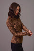 Woman wearing a brown patterned long-sleeve top against a gray background
