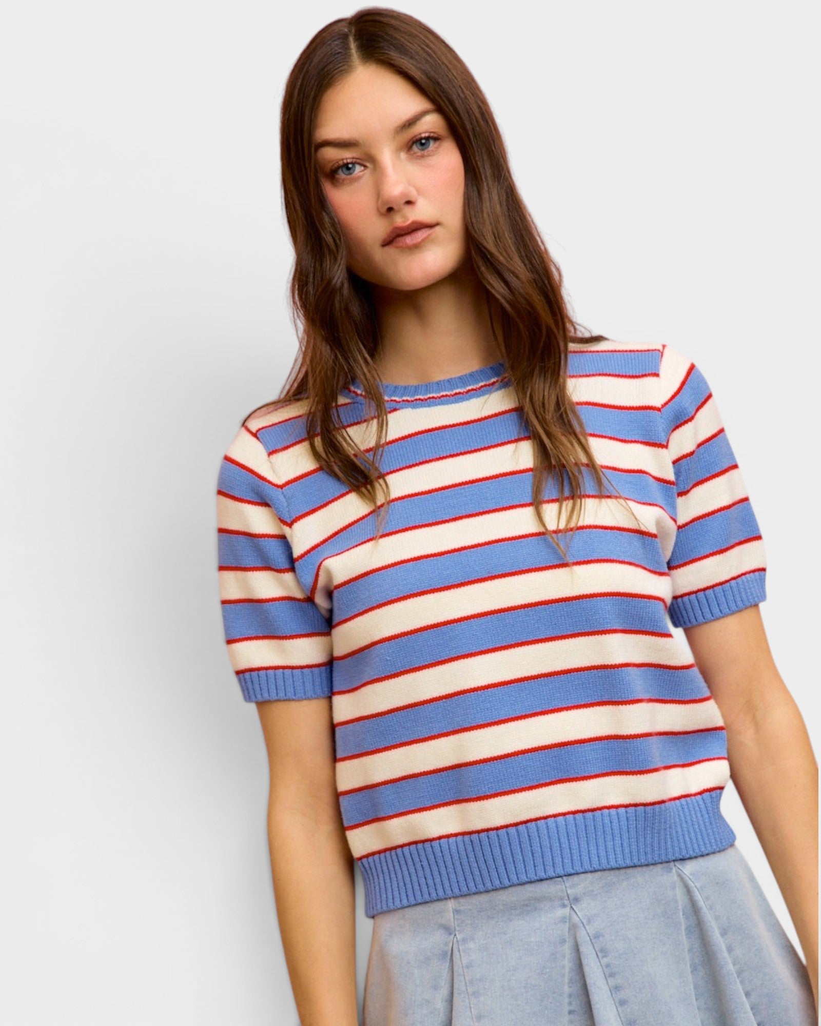 Woman wearing a blue, red, and white striped sweater against a plain background