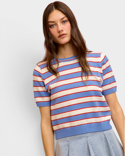 Woman wearing a blue, red, and white striped sweater against a plain background